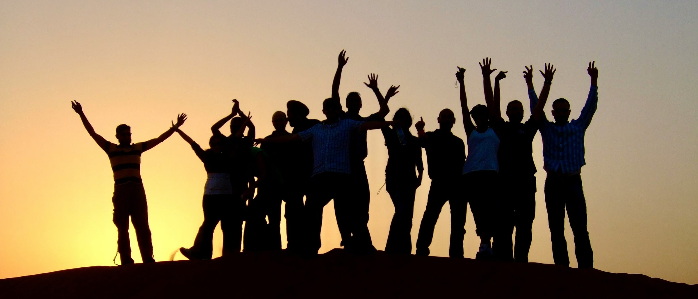 A group of people silhouetted along a ridge against a low sun