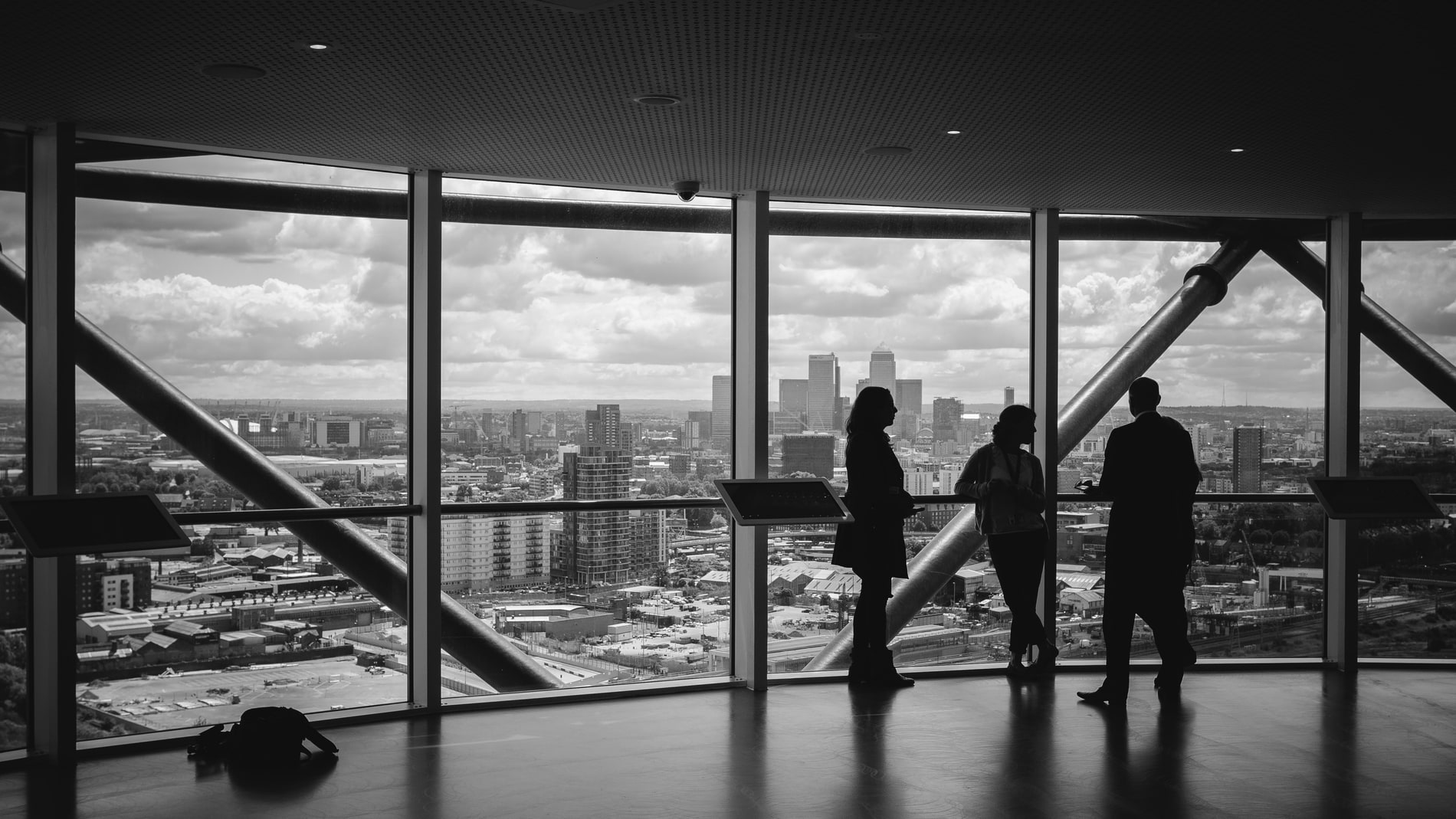 People standing at a window wall high above a city, looking out over it