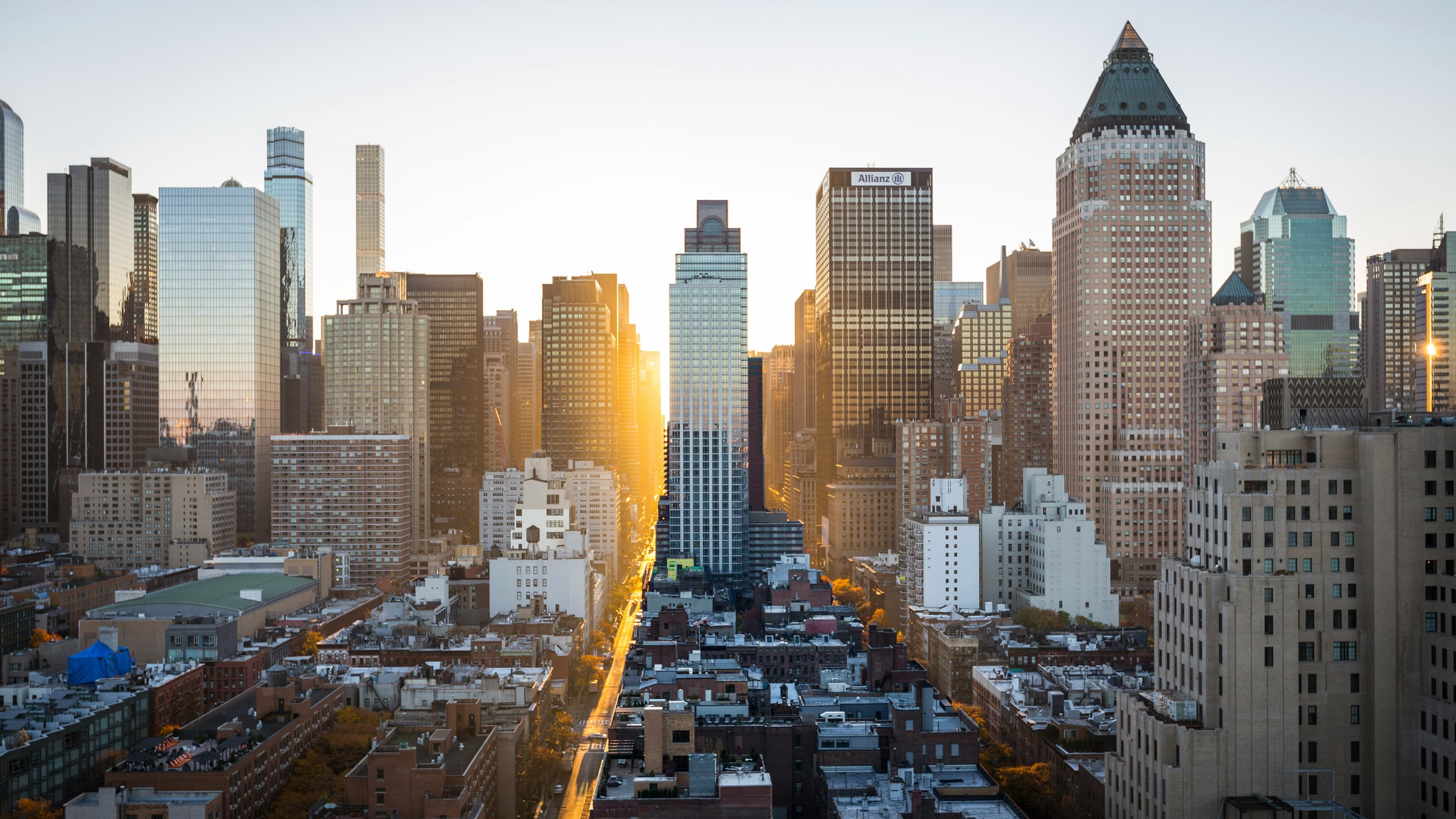A city skyline at the end of the day, with the sun low at the end of an avenue