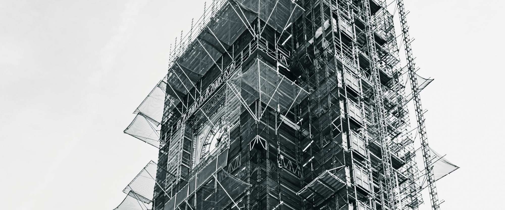A clock tower under restoration, wrapped floor to floor in scaffolding